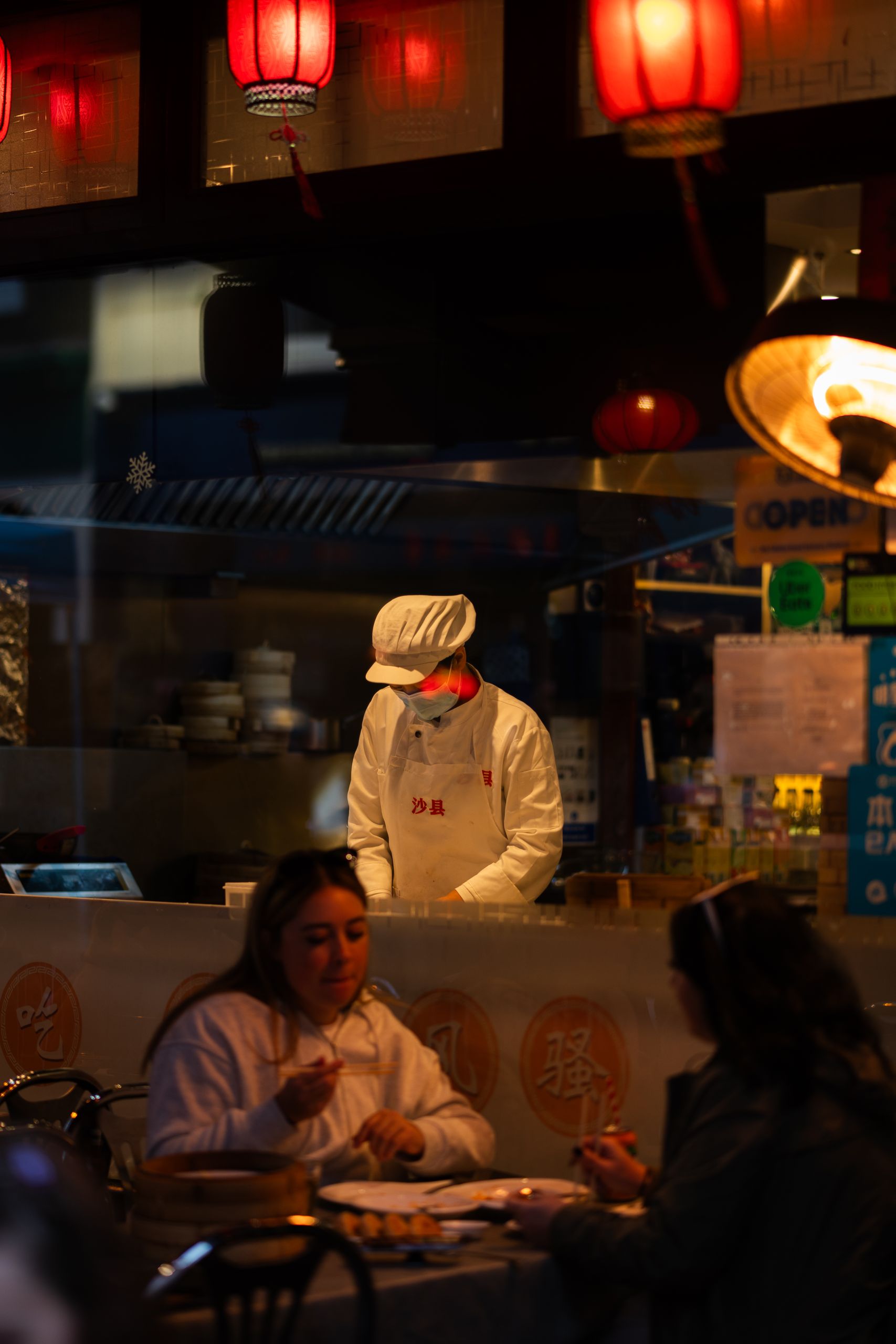 Clients profitant d’un repas asiatique sous des lanternes dans une ambiance chaleureuse